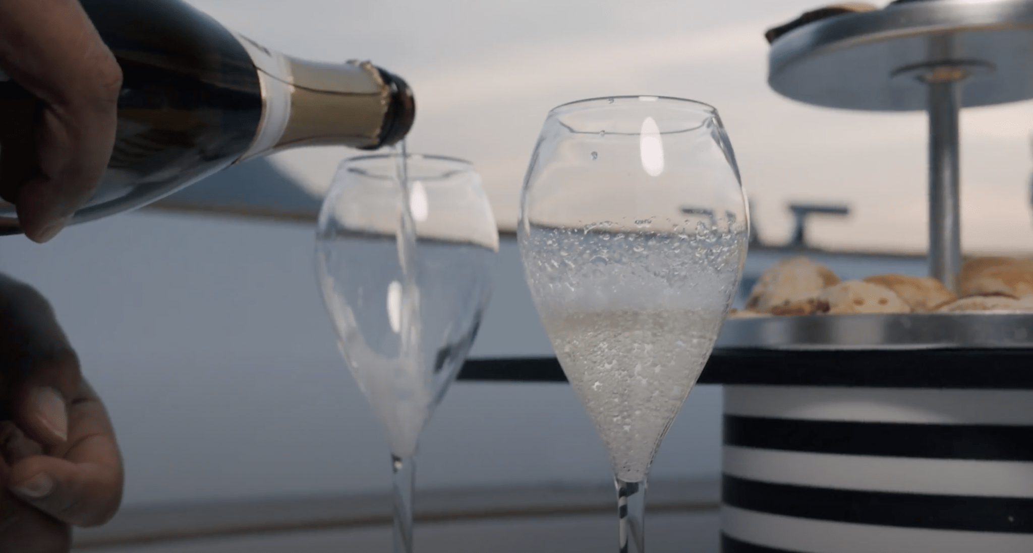 A waiter is preparing champagne during a boat tour on lake Como with aperitif at the sunset