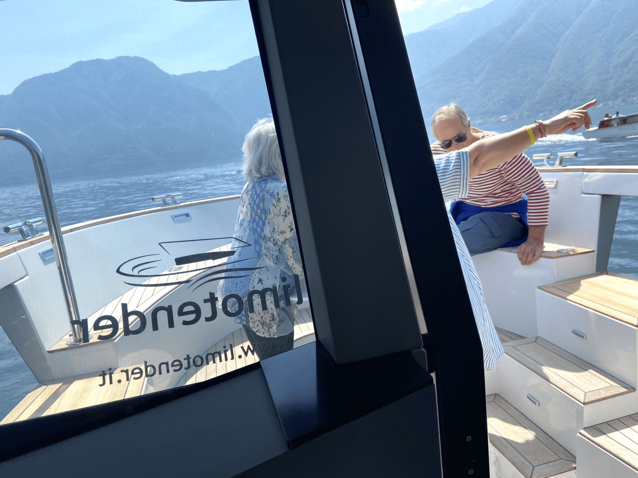 high quality boat rental company offers its Limotender for lake como guided tours on the bow of the boat with guide pointing the finger at the main sights