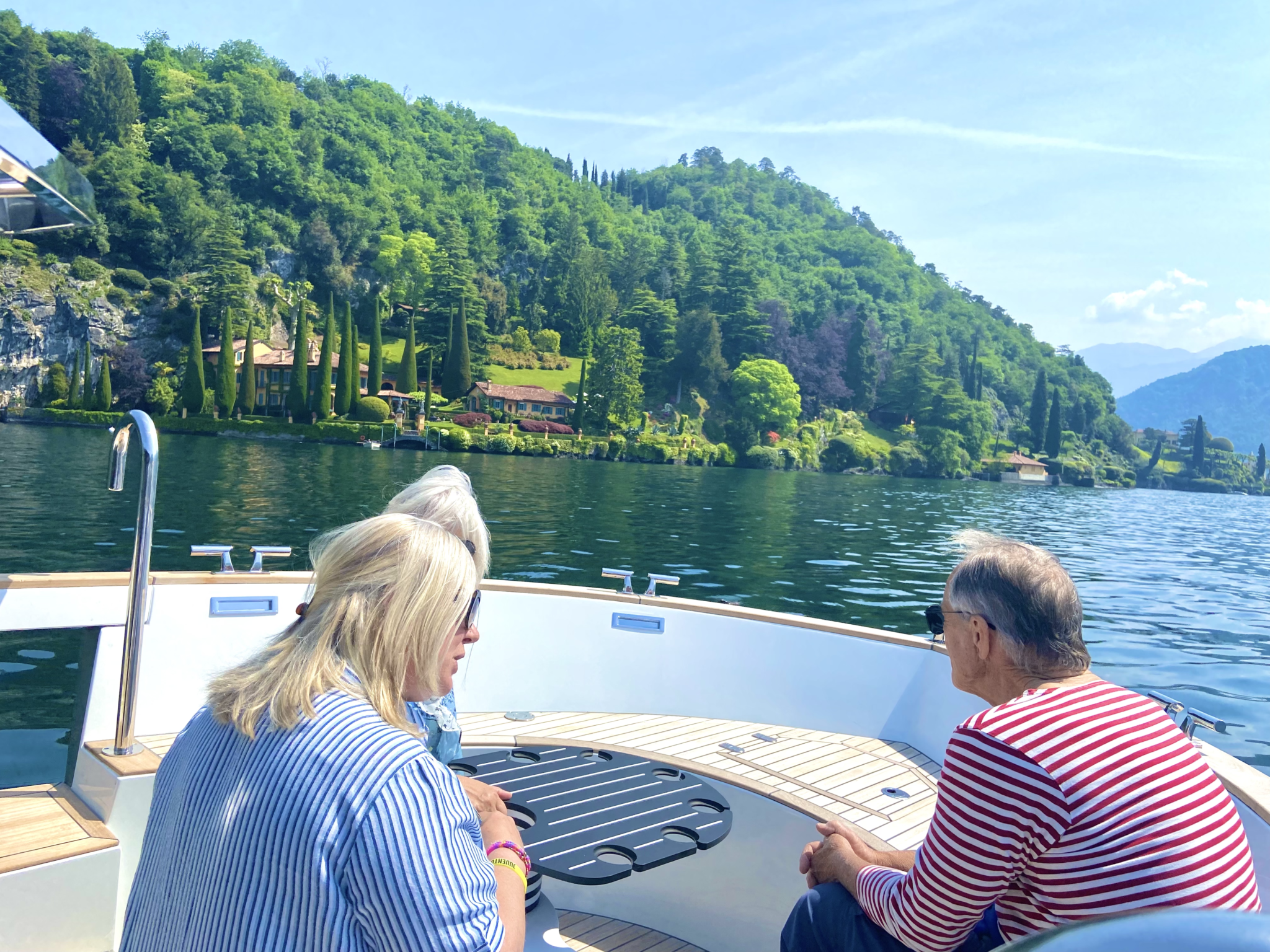 Blonde english speaking local guide takes tourists to a lake como guided tour while sitting on a private boat surrounded by nature as they rent a boat in Bellagio